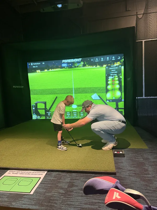 A young golfer getting a grip lesson in a bay.