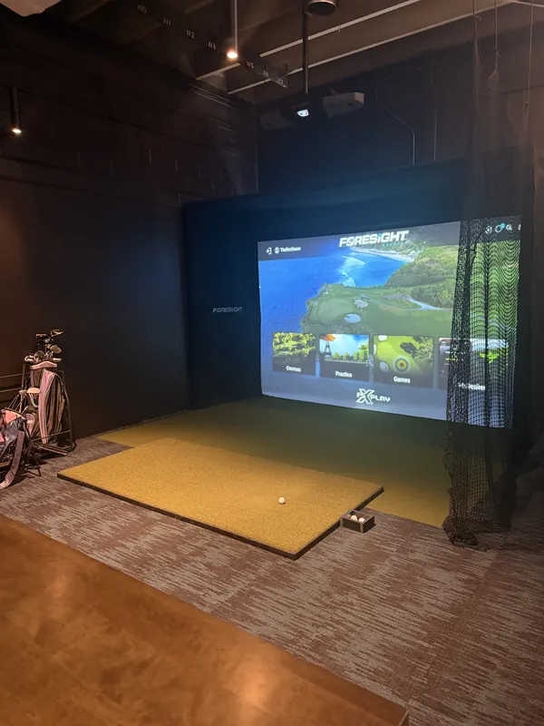 A Foresight simulator bay ready to play, with clubs on the rack.